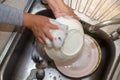 TheÃ¢â¬â¹ Hand cleaning of female or housewife woman washing dishes with a yellow sponge in kitchen sink Royalty Free Stock Photo